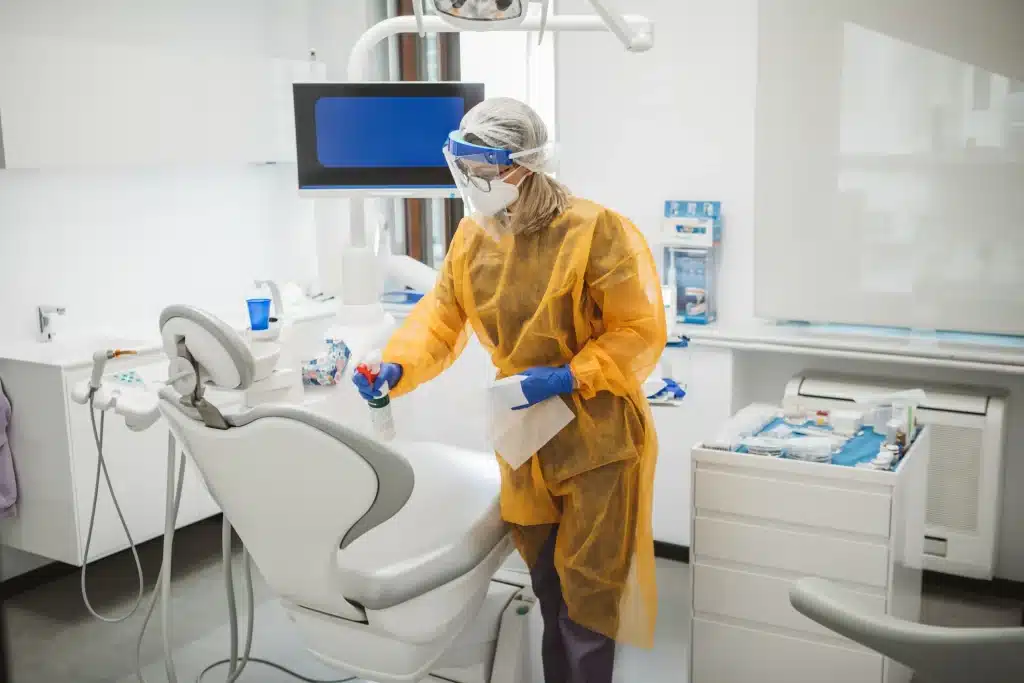 Dental office cleaning services in Calgary with technician in PPE sanitizing a dental operatory