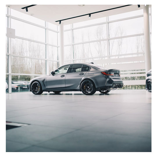 A spotlessly clean car dealership showroom with gleaming vehicles on display.